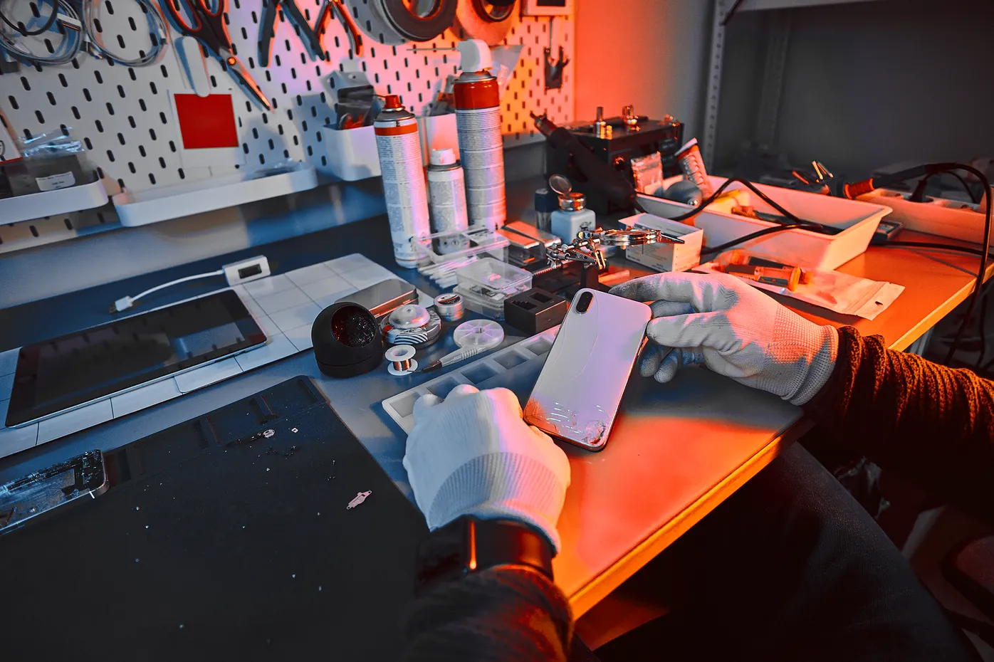 Técnico con guantes revisando un celular en la mesa de trabajo del taller de ArmalyTech